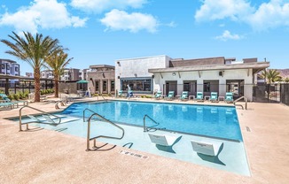 Luxurious modern apartment complex featuring a sparkling swimming pool with sun loungers and lush palm trees, perfect for relaxation and leisure at Summit on Boulder Apartments.