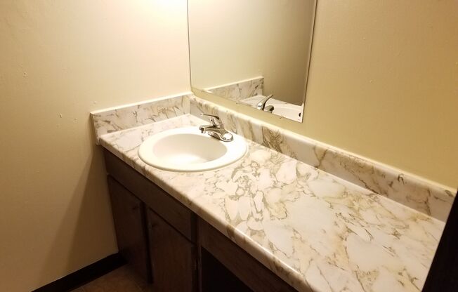 A bathroom sink with a marble countertop and a mirror above it.