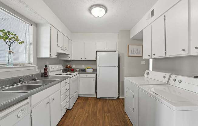 A white kitchen with wooden floors and white appliances.