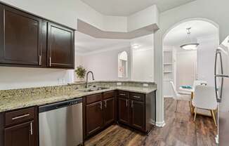 A kitchen with dark brown cabinets and granite countertops.