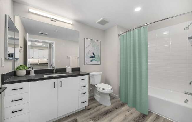 a bathroom with white cabinets and a green shower curtain