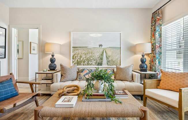 A living room with a sofa, a table with a plant, and a painting on the wall.