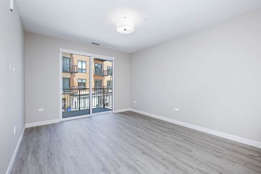 A spacious room with a view of a building through a glass door.