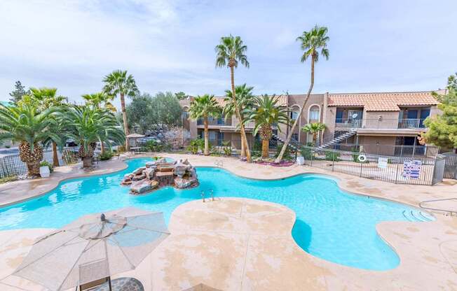 A large swimming pool surrounded by palm trees and a few other trees.