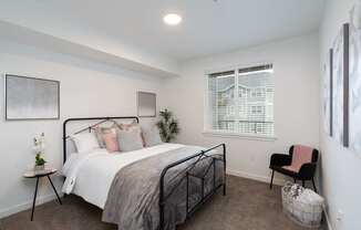 A bedroom with a bed, chair, and a window with blinds.