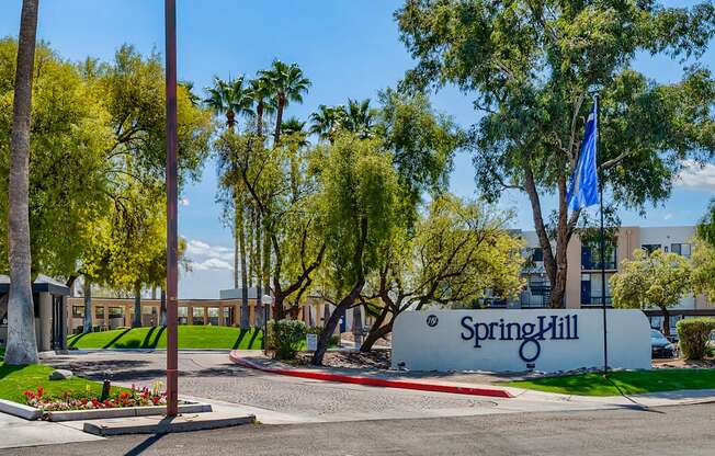 a view of the entrance to the spring hill campus with trees and a blue sign