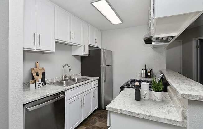 Model Kitchen with White Cabinets and Wood-Style Flooring at The Meritage Apartments in Vallejo, CA.