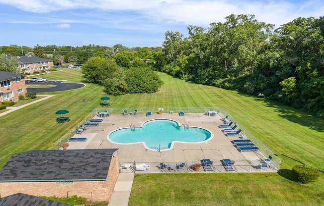 an aerial view of a pool and lawn with chairs around it