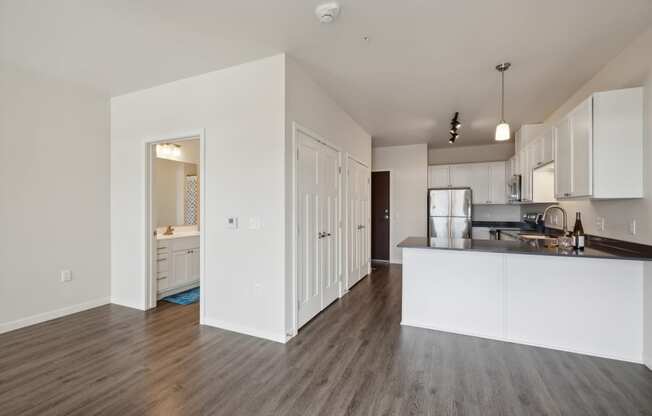 an open kitchen and living room with white walls and wood flooring