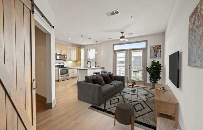 A modern living room with a grey couch and a glass coffee table.