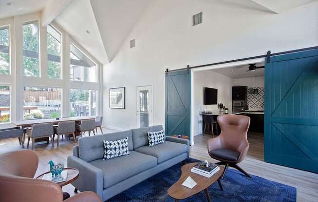 A living room with a grey couch and brown chairs.