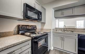 a kitchen with white cabinets and a black stove and microwave
