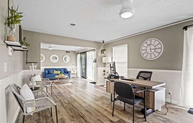 a home office with a desk and chairs and a living room with a couch and a tv at Beacon Hill and Great Oaks Apartments, Rockford