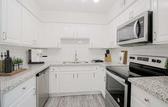 A modern kitchen with white cabinets and a black stove top oven.