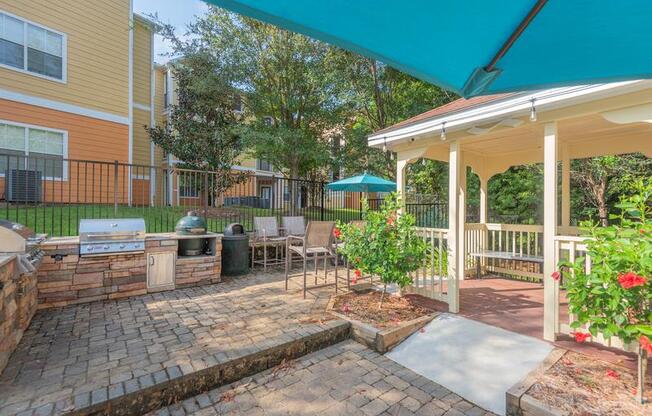 Tallahassee FL apartment complex grilling pavilion with two grills, lounge chairs, brick flooring, and a roofed sitting area at Evergreens at Mahan