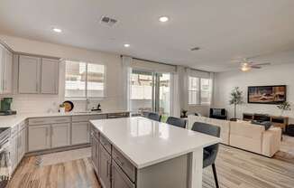 A modern kitchen with a large island and a living area with a couch.