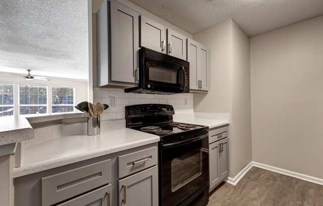 a kitchen with white cabinets and a black stove top oven