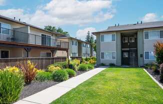 View of courtyard with exterior building in back ground and lush landscaping around private patio/balcony