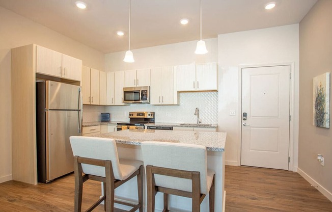 a kitchen with a marble counter top and a stainless steel refrigerator