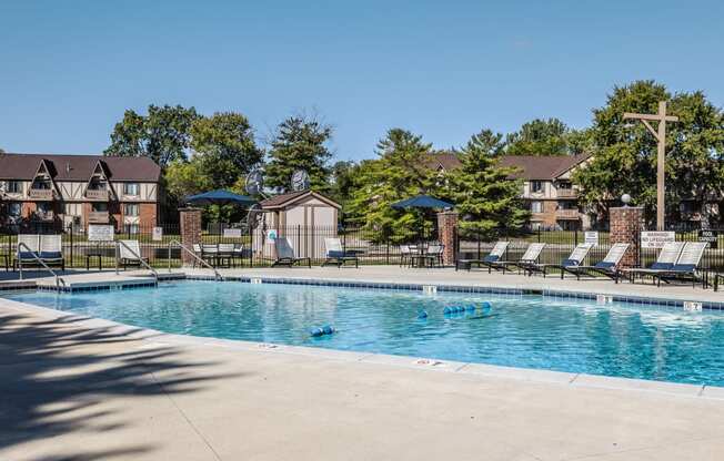 a swimming pool with chairs and umbrellas in front of apartment buildings East Indianapolis