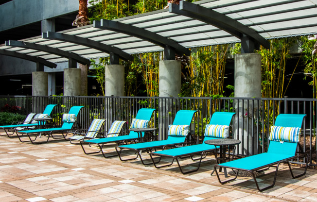 Luxurious lounge chairs under awning poolside at Millenia 700 Apartment Homes
