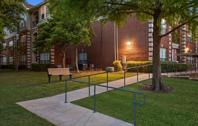 A park area with a bench, a tree, and a walkway.