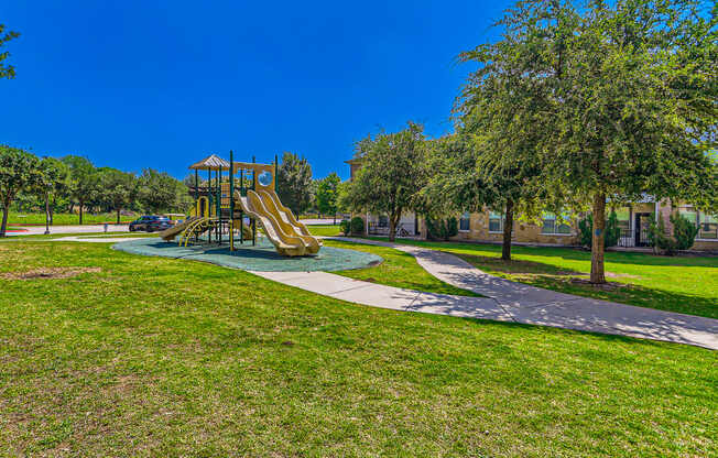 a playground in a park with green grass and trees at Discovery at Craig Ranch, McKinney, Texas