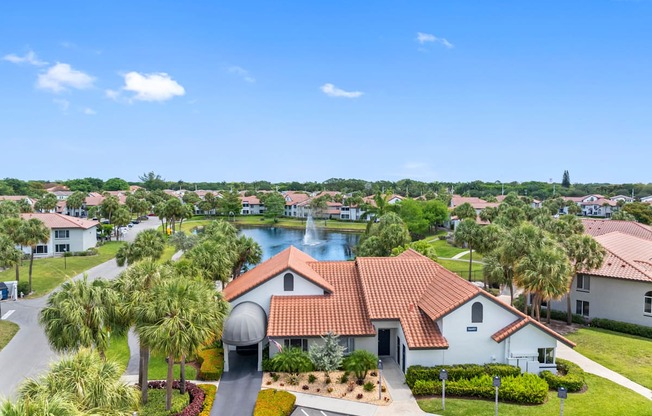 A view of a residential area with a house in the foreground and a body of water in the background.