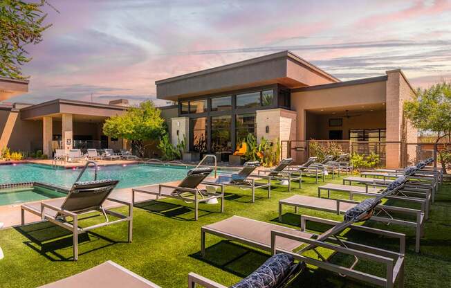 A modern house with a pool and lounge chairs.