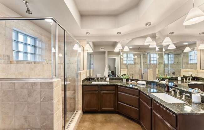 A large, well-lit bathroom with a walk-in shower and double sinks. at Bridge at Heritage Woods, Austin, TX