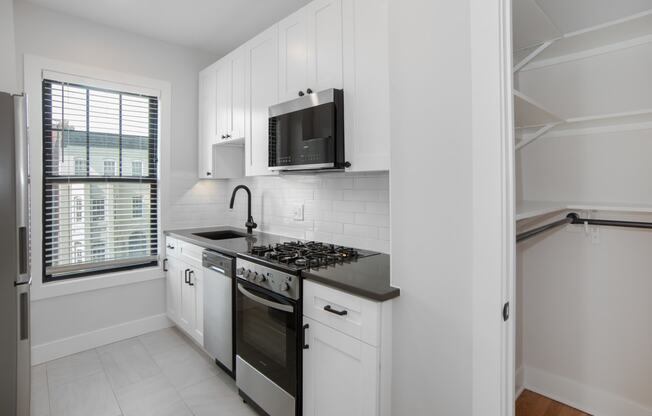 a kitchen with white cabinets and a stove and a microwave