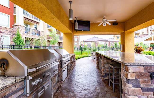 A patio with a stone wall and a grill.