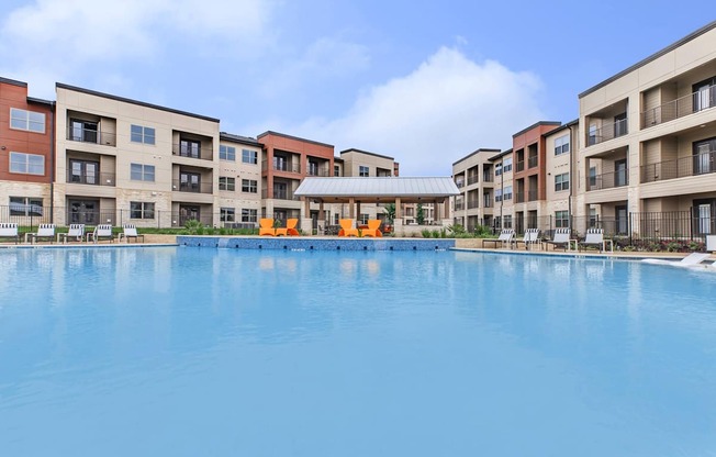 A large swimming pool in front of apartment buildings.
