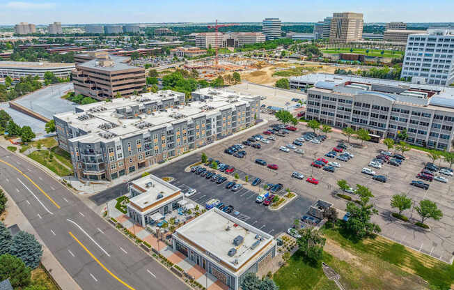 an aerial view of a large parking lot with several buildings in the background
