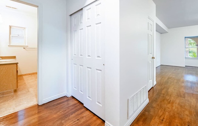 Hallway view of closet space with a view of a bathroom