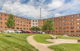 a large brick building with a park in front of it