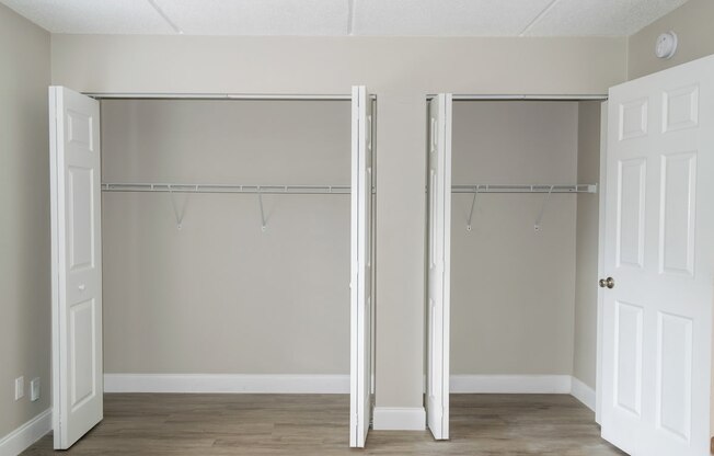 an empty bedroom with two closet doors with hangers