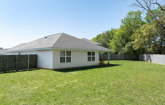 the backyard of a white house with a yard and a fence