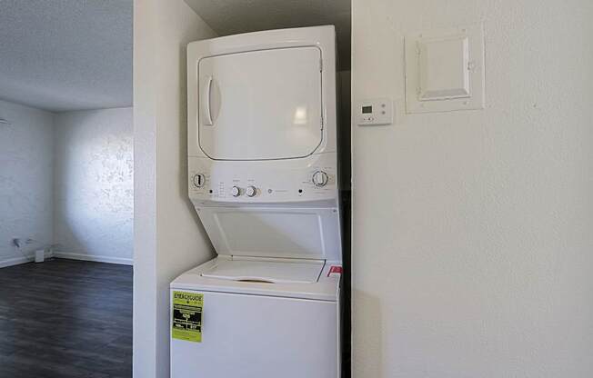 A white dishwasher with a yellow caution label on the door is in a room with white walls.