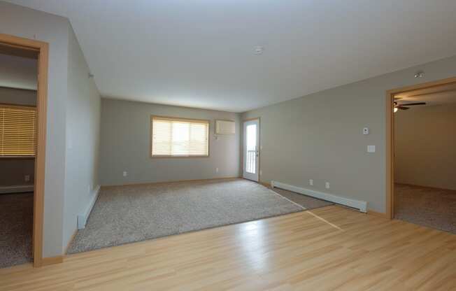 an empty living room with wood floors and a window. Fargo, ND Urban Plains Apartments