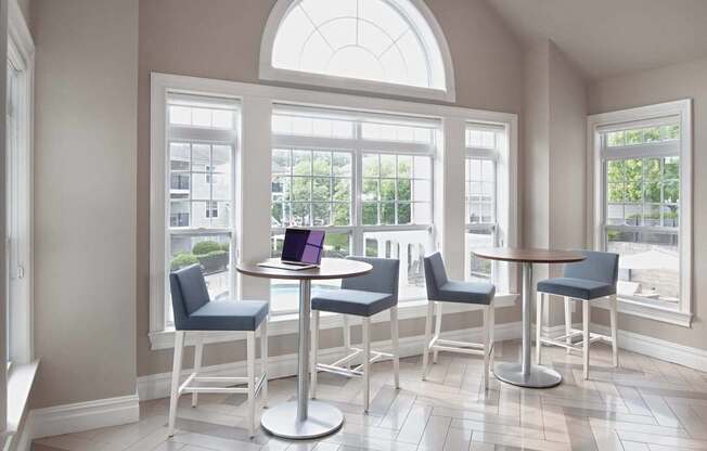 a living room with tables and chairs and a laptop