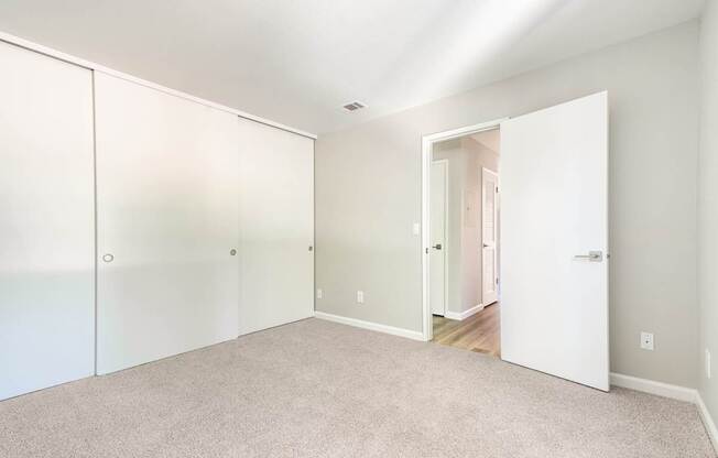 A white room with a carpeted floor and a white door.
