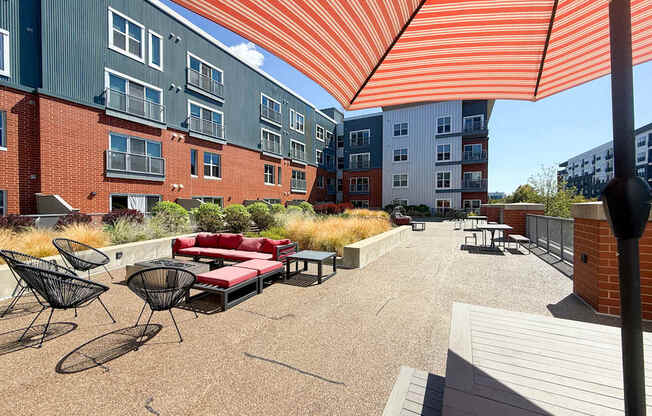 A patio with a red couch and chairs under a striped orange and white awning.