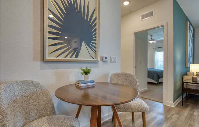 A modern dining room with a round wooden table and two chairs.