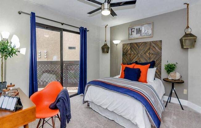 A bedroom with a bed, chair, and a ceiling fan.