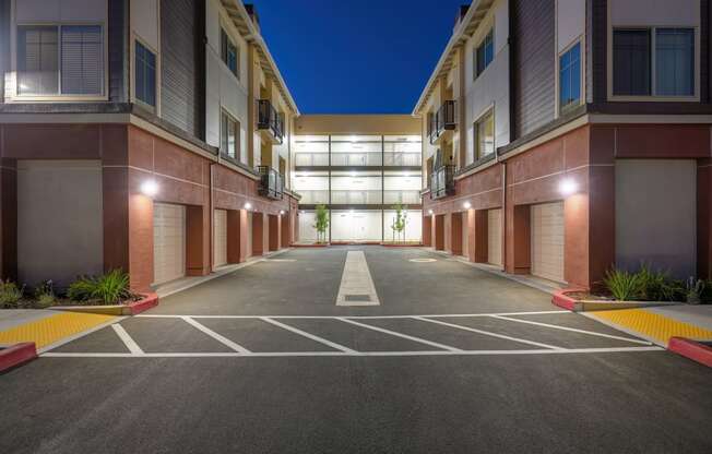 an empty parking lot in front of an apartment building at night