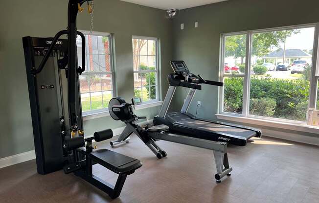 A gym with a treadmill, a stationary bike, and a weight machine.