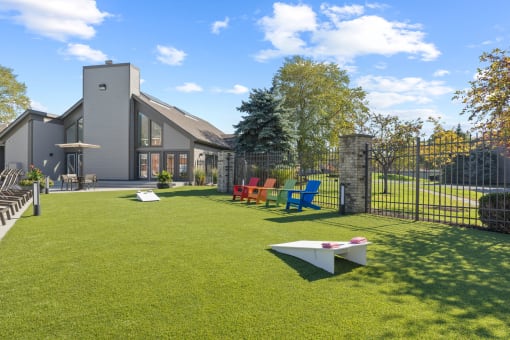 a yard with a fence and chairs and a house in the background