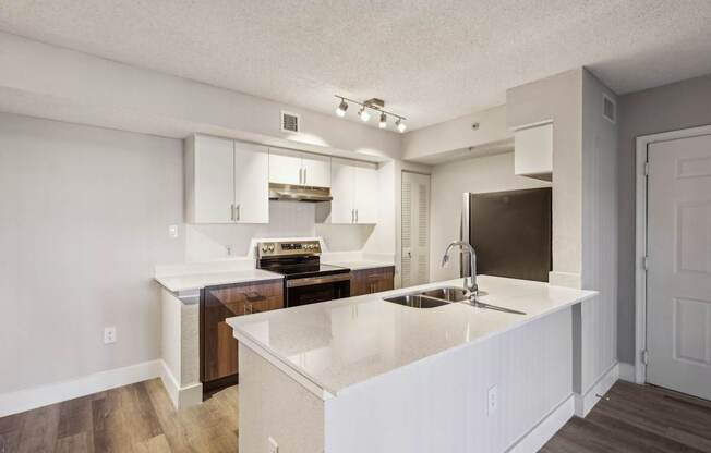 A kitchen with white countertops and wooden floors.