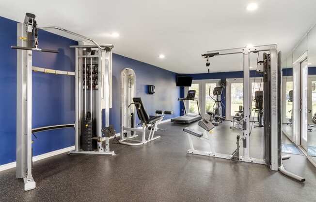 a gym with weights and cardio equipment and blue walls